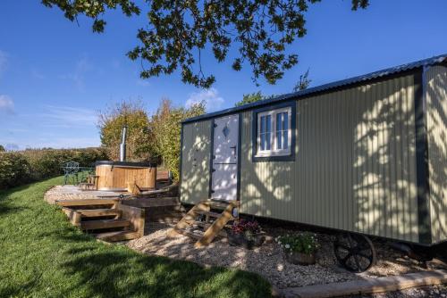 a green tiny house with a hot tub in a yard at Abbey Farm Glamping & Cottage in Thame