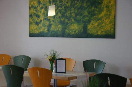 a dining room with a table and chairs and a painting at EuroHotel Günzburg in Günzburg