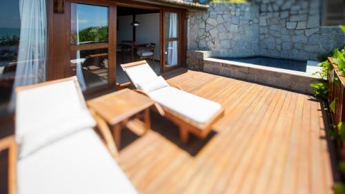 a wooden deck with two chairs and a backdoor at Hotel Sombra e Água Fresca in Pipa