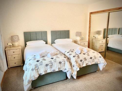ein Schlafzimmer mit zwei Betten und einem großen Spiegel in der Unterkunft Ardlinnhe Cottage in Fort William