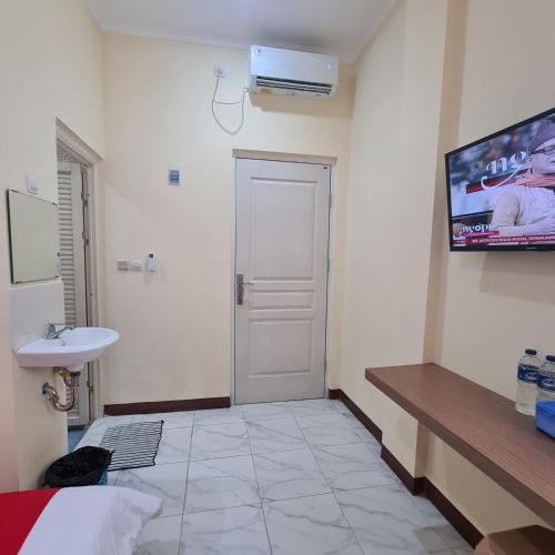 a bathroom with a sink and a tv on the wall at RedDoorz near Tugu Muda Semarang in Kalibanteng-lor