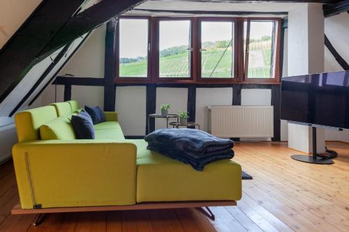 a living room with a yellow couch and a flat screen tv at Fachwerkhäuschen in Enkirch