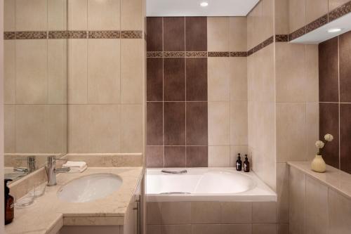 a bathroom with a white tub and a sink at Staybridge Suites Dubai Internet City by IHG in Dubai