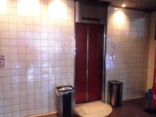 a bathroom stall with a red door and two trash cans at Park Inn in Osaka