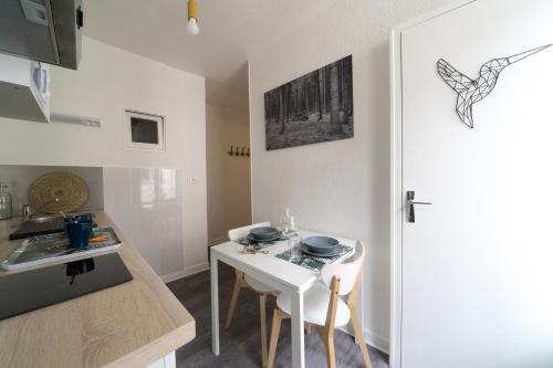 a small kitchen with a white table and a white door at AppartUnique - Chez Majorelle in Vichy