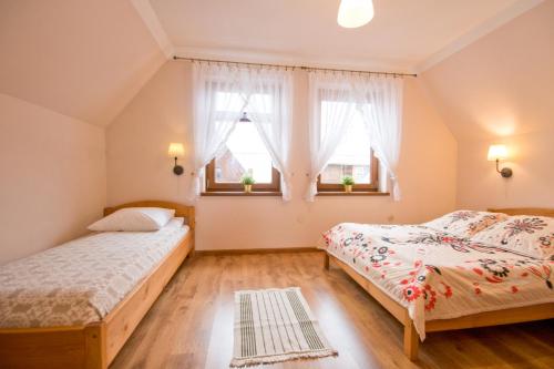 シャフラリにあるDomek przy Termach - Bańska Niżnaのベッドルーム1室(ベッド2台、窓2つ付)