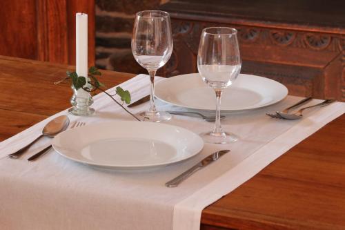 a table with two plates and two wine glasses at La Villauvert - Cottage in Saint-Martin-sur-Oust