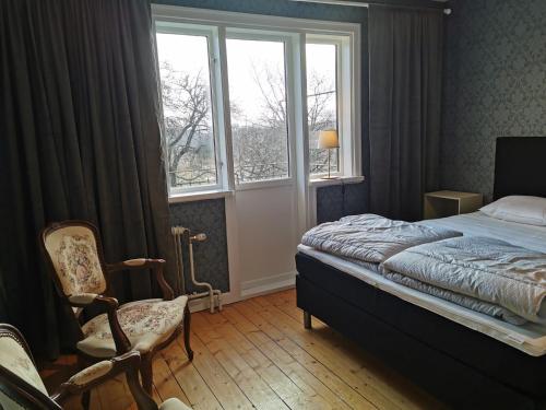 Östra Flygeln Grinda Säteri في Malmköping: غرفة نوم بسرير ونافذة وكرسي