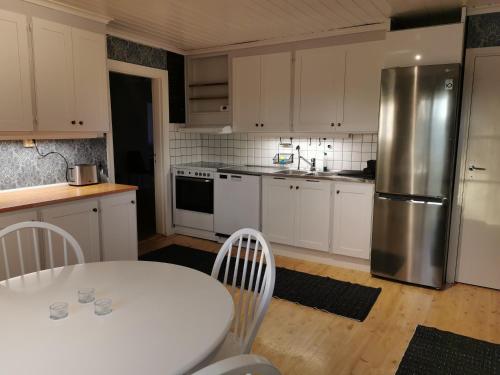 a kitchen with a white table and a stainless steel refrigerator at Östra Flygeln Grinda Säteri in Malmköping