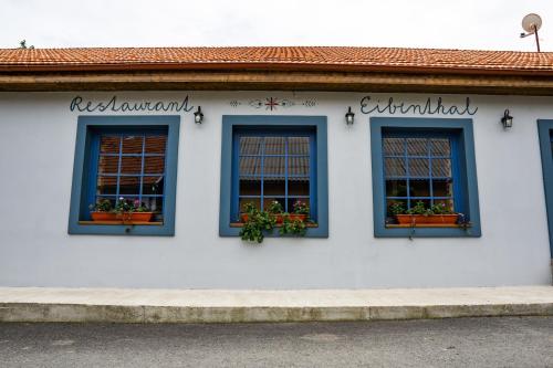 a white building with three windows with plants in them at Apartments Eibenthal in Eibenthal