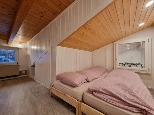 a bed with pink pillows in a small room at Zum Lerch Penthouse in Saas-Fee