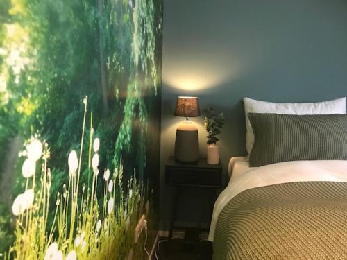 a bedroom with a bed with a large painting on the wall at Maison La Rootz! in Noordbroek