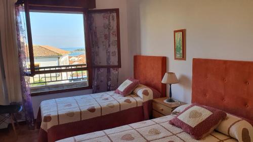 1 dormitorio con 2 camas y ventana con vistas en Tercero Loft Susana, en San Vicente de la Barquera