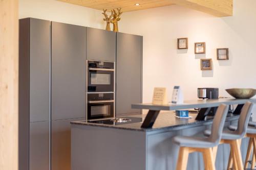 a kitchen with a stainless steel refrigerator and stools at Bergresort Hauser Kaibling by ALPS RESORTS in Haus im Ennstal