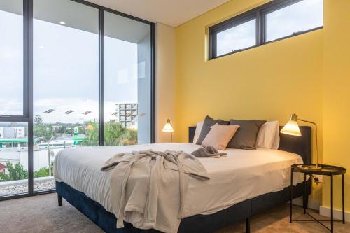 シドニーにあるKULA Apartments Parramattaのベッドルーム1室(黄色い壁と窓のあるベッド1台付)
