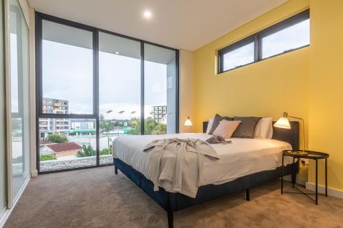 um quarto com uma cama e janelas grandes em KULA Parramatta em Sydney