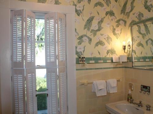 baño con lavabo y ventana con flores en la pared en The Beech Tree B&B en Rockport