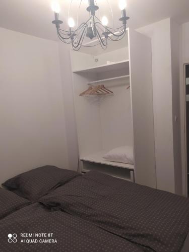 a small bedroom with a bed and a chandelier at Apartament Brzechwy in Poznań