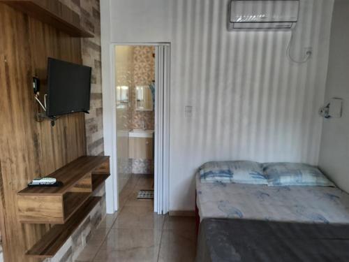 1 dormitorio con 1 cama y TV en Moradas Jeane, en Guarda do Embaú