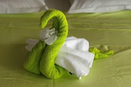 a green towel with a flower on a bed at Le Lis Vacances et Affaire Cosy vue Mer in Le Lamentin
