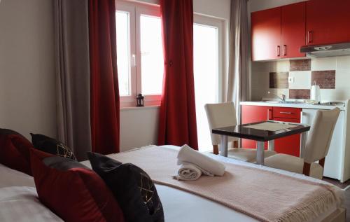 um quarto com uma mesa e uma cozinha com armários vermelhos em Apartments Emilija em Brela