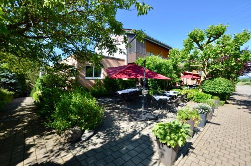 un patio con mesas y sombrillas frente a un edificio en Hotel Höllsteiner Hof en Steinen