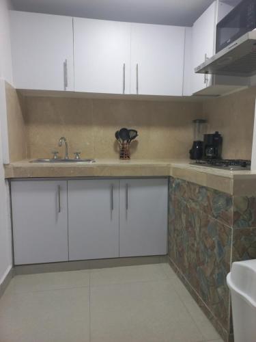 een keuken met witte kasten en een wastafel bij La casita de max y tim apartaestudio 4to piso in Cartagena