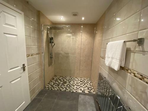 een badkamer met een douche, een glazen deur en een tegelvloer bij The Crest Hillside Retreat With Hot Tub in Abertillery