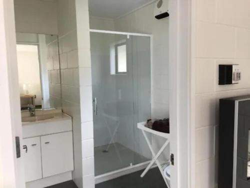 een witte badkamer met een douche en een wastafel bij Mackenzie Motels in Fairlie