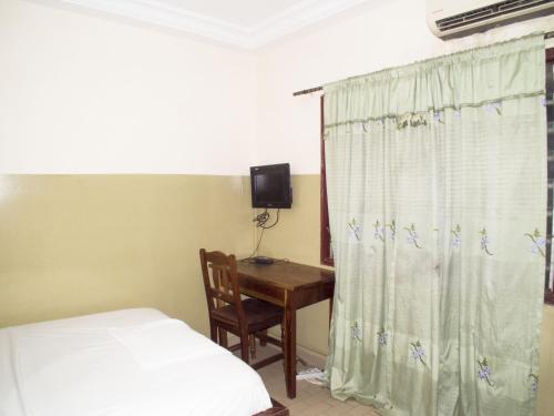 a bedroom with a bed and a desk and a curtain at Royal hotel in Lomé