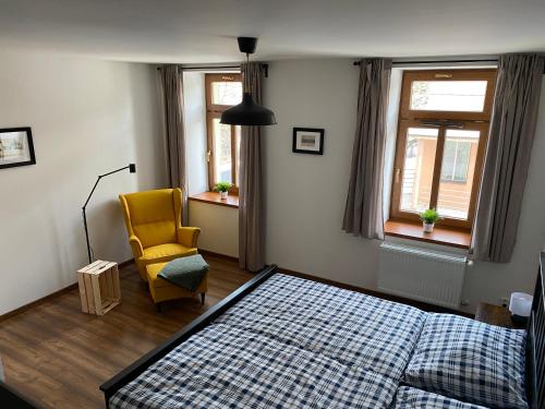 a bedroom with a bed and a yellow chair at Apartmán U Pátka in Rýmařov