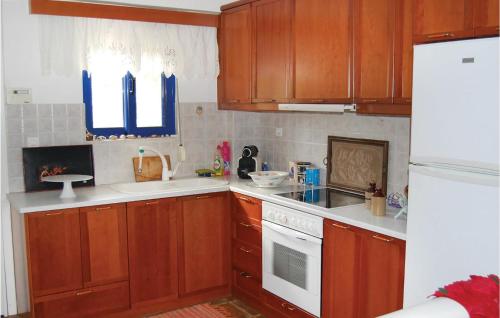 a kitchen with wooden cabinets and a white stove top oven at Pet Friendly Apartment In Melissi With Wifi in Melission