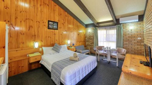 una camera con un letto in una stanza con pareti in legno di All Travellers Motor Inn a Coonabarabran