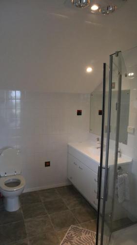 a bathroom with a toilet and a glass shower at Luxury Holiday home with cliff top sea and city views in Whangaparaoa