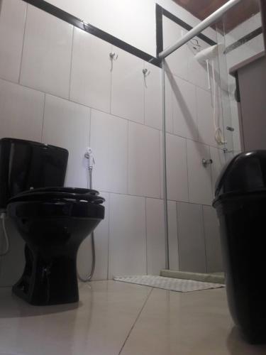 a bathroom with a black toilet and a shower at Vista Verde in Morro de São Paulo