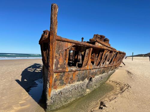 an old boat sitting on the beach at Torquay Terrace Bed & Breakfast in Hervey Bay