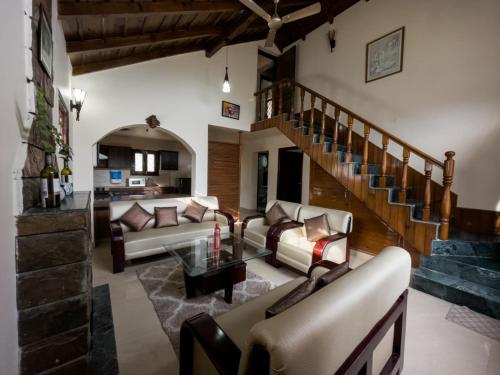 a living room with couches and a staircase at Karinya Villas in Nainital