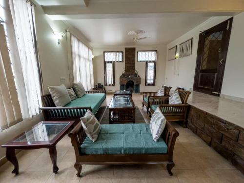a living room with couches and a fireplace at Karinya Villas in Nainital