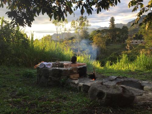 a man sitting in a bath tub next to a fire at Glamping El Árbol en la Casa in San Antonio del Tequendama