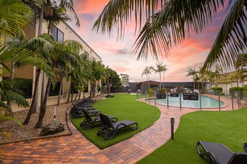 a courtyard with a row of chaise lounges and palm trees at Nightelier Mermaid Waters in Gold Coast