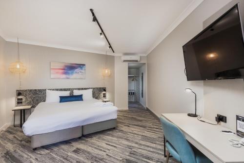 a hotel room with a bed and a flat screen tv at Nightelier Mermaid Waters in Gold Coast