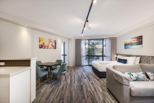 a hotel room with a bed and a couch and a table at Nightelier Mermaid Waters in Gold Coast