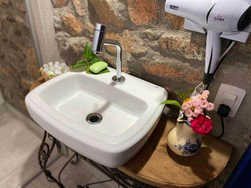 a white sink in a bathroom with flowers in a vase at Segredo da Serra Guest House in Tiradentes