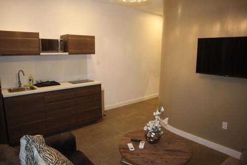 a kitchen with a table and a tv on the wall at Empire Apartments SU 2 Marthastraat in Paramaribo