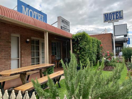 
a row of wooden benches in front of a brick building at Yarragon Motel in Yarragon
