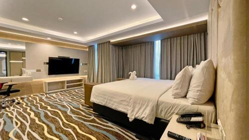 a hotel room with a bed and a flat screen tv at Swiss-Belhotel Makassar in Makassar