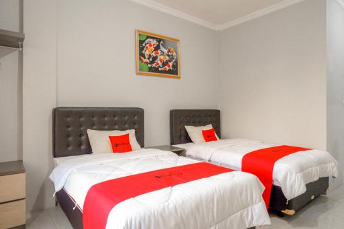 two beds in a room with red and white sheets at RedDoorz near Jalan Adi Sucipto Solo in Solo