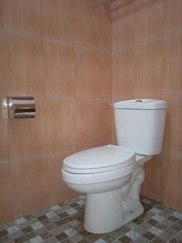 a white toilet in a bathroom with wooden walls at Madu Tiga Beach and Resort in Tanjung Pinang 
