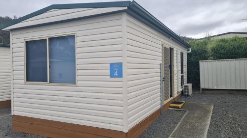 a small white shed with a blue sign on it at Discovery Parks - Mornington Hobart in Hobart
