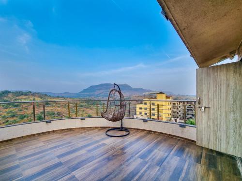 a balcony with a wicker chair on a wooden floor at Pooja Villa Suites-Rooms and Pool, Igatpuri in Igatpuri